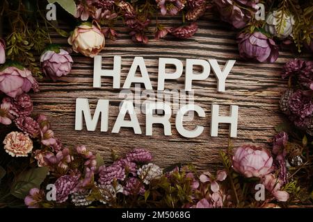 Happy March alphabet letters with flowers frame on wooden background Stock Photo