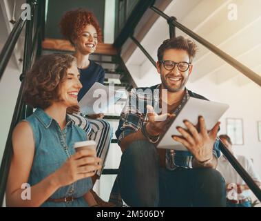 Creativity is always better shared. creative employees having a discussion on the staircase at work. Stock Photo