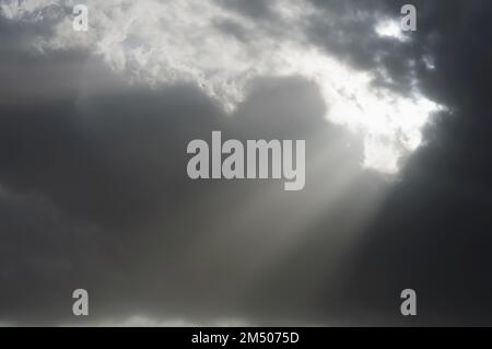 Gloomy dark sky with rays of light breaking through the clouds. Dramatic skies, enlightenment and blessings Stock Photo