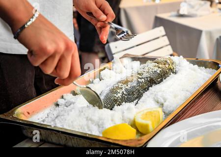 Branzino or Mediterranean sea bass whole roasted in salt fish filleted at the table by a waiter at a street restaurant in Vernazza, Cinque Terre Italy Stock Photo