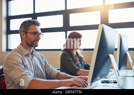 Working hard on their latest designs. two designers working on computers in an office. Stock Photo