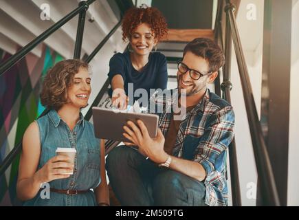 Productivity is everything. creative employees having a discussion on the staircase at work. Stock Photo