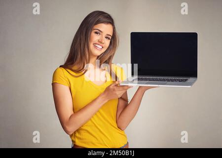 Nothing is stopping me from surfing the net now. an attractive young woman holding a laptop with a blank screen against a grey background. Stock Photo