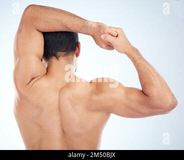 Man, fitness stretching and back view for muscle wellness, body care and sports exercise or warm up in studio. Athlete, arm stretch and bodybuilder Stock Photo