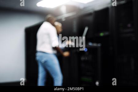 System administrators to the rescue. two IT technicians using a computer while working in a server room. Stock Photo