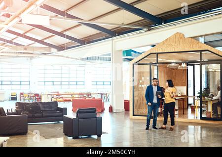 Technology enables them to come up with better strategic plans. two designers working on a digital tablet together in an office. Stock Photo
