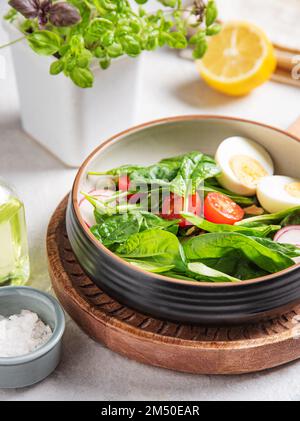 Fresh salad of green spinach leaves, tomatoes, microgreens basil, boiled egg, red radish and olive oil with flax seeds. The concept of healthy, dietar Stock Photo