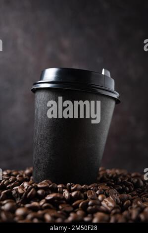 black paper cup with coffee beans on a dark background close up and macro. The concept of eco and zero waste. Eco-friendly use. Mock up and copy space Stock Photo