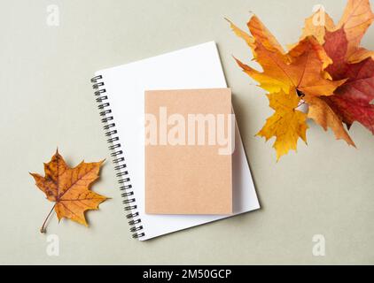 Concept autumn flat lay with yellow maple leaves,  notebook and notepad  on a pastel green background. Top view and copy space. Stock Photo