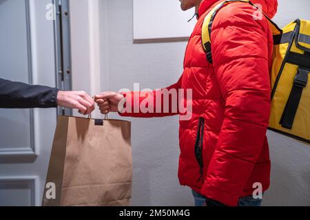 Unrecognizable food delivery man delivers bag of food to a customer who has ordered online. Stock Photo