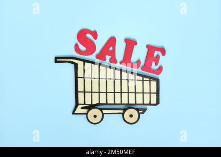 Shopping sale concept. Wooden shopping cart with word sale in blue background. Stock Photo