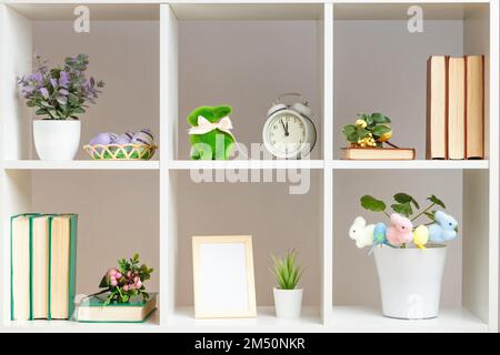 Home interior, elements of Easter decor. White shelves with books photo frame rabbits eggs Stock Photo