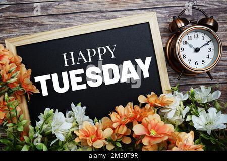 Happy Tuesday typography text written on wooden blackboard with flower bouquet decorate on wooden background Stock Photo