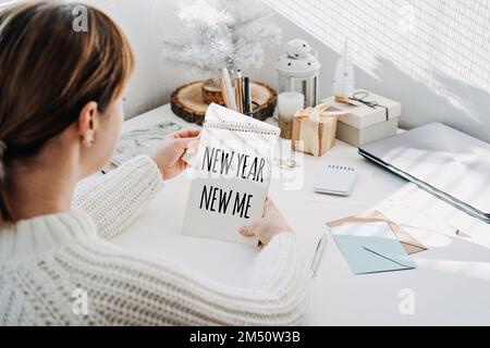 NEW YEAR NEW ME text in open notepad in womans hand on table at home. Setting goals and new years resolution. New year loading. Stock Photo