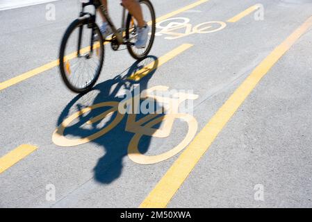 Cycling person shadow on marked bicycle lane Stock Photo