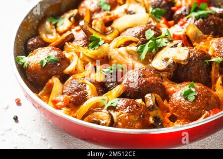 Meatballs with mushrooms in tomato sauce in a frying pan. Stock Photo