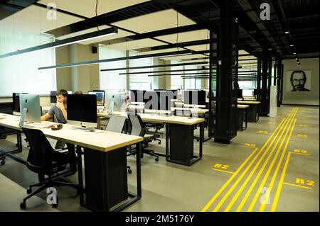 Young people working at laptops at the large computer room, portrait of Steve Jobs on a background. January 23, 2020. Kyiv, Ukraine Stock Photo