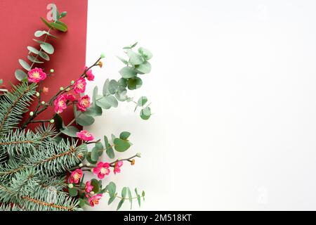 Pink magnolia flowers on fresh eucalyptus and fir twigs. Decorative corner element, flat lay on white background. Copy-space, place for greeting text. Stock Photo