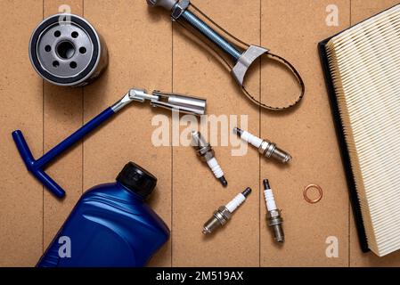 Bottle of motor oil, oil filter, air filter, sparking plugs, spark plug key and oil filter wrench on wooden background. Car repairing service concept. Stock Photo