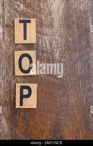 The word top written in small wooden blocks on a rustic background. Free space to write. Stock Photo