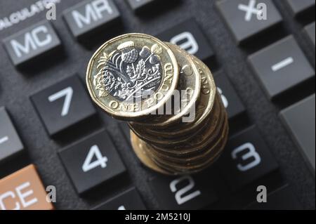STACK OF ONE POUND COINS ON CALCULATOR RE COST OF LIVING CRISIS PENSIONS INCOME INFLATION HOUSEHOLD BUDGETS ETC UK Stock Photo