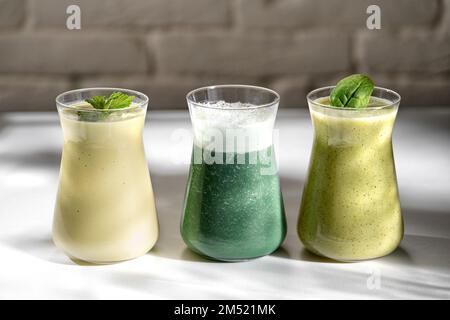 Freshly blended fruit smoothies of various colors and tastes in glass jars. Yellow green. Bright sunlight on the background Stock Photo