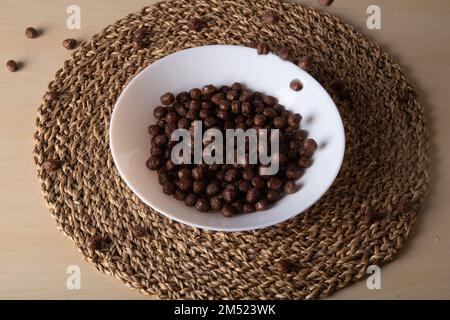photo of dried chocolate balls lying in a deep plate on a straw stand Stock Photo