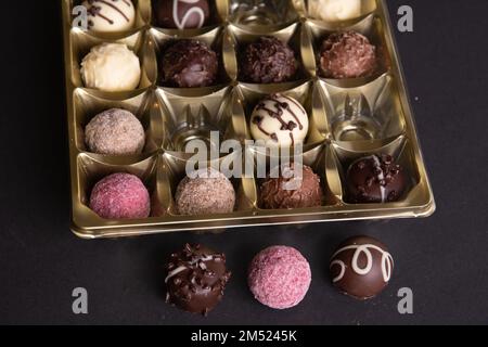 photo chocolates in a package several chocolates lying next to each other on a black background Stock Photo