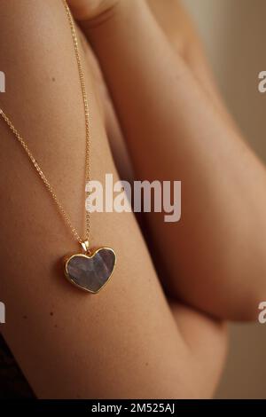Gold heart-shaped amulet on a girl's shoulder Stock Photo