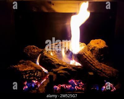 Glowing logs in the fireplace with flames and embers Stock Photo