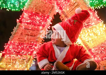 Lalitpur, Nepal. 24th Dec, 2022. A girl dressed as Santa Claus poses for photos in front of the Christmas decorations during Christmas Eve at the Lalitpur shopping center. Christmas Eve is the evening or entire day before Christmas Day, the festival commemorating the birth of Jesus Christ. Christmas Day is observed all-around the world. (Photo by Prabin Ranabhat/SOPA Images/Sipa USA) Credit: Sipa USA/Alamy Live News Stock Photo