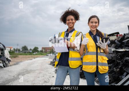 Mechanical woman owner small business inspecting standing in the car junkyard, Dirty male repairman choosing spare parts on car junkyard, Used of vehi Stock Photo