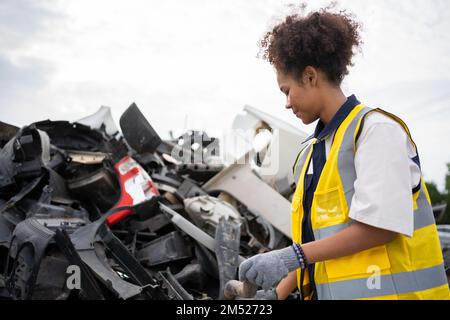 Mechanical woman owner small business inspecting standing in the car junkyard, Dirty male repairman choosing spare parts on car junkyard, Used of vehi Stock Photo