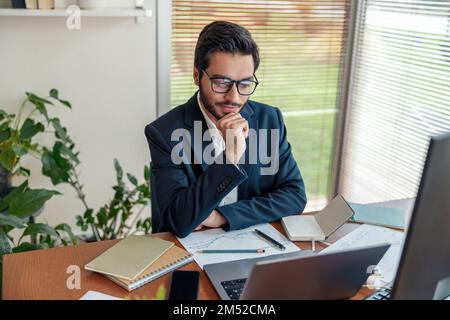 Focused indian businessman in suit working with documents from home office  Stock Photo