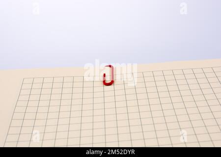 Colored paper clip on a checked notebook page Stock Photo