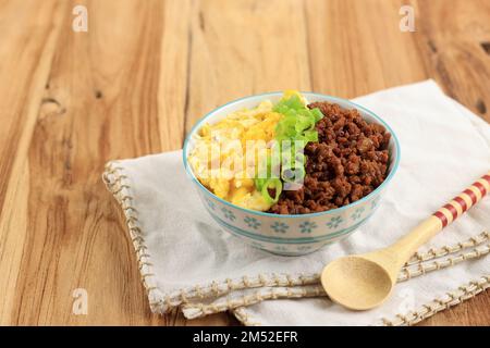Japanese Spicy Beef Soboro with Scrambled Egg, Rice, and Green Onion. Copy Space for Text on Wooden Table Stock Photo