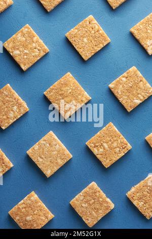 coconut biscuits pattern, crispy square shaped homemade cookies on textured blue surface, flat lay food background Stock Photo