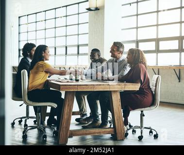 Were happy to have you on board. two business colleagues shaking hands over the boardroom table during a meeting. Stock Photo