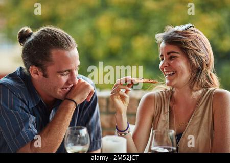 Calories dont count on the weekend. two happy young friends sharing a pizza outside. Stock Photo