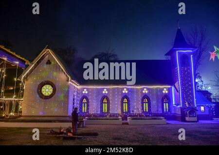 Srinagar, India. 24th Dec, 2022. A security guard warms himself in font of the bonfire outside the Holy Family Catholic Church on the eve of Christmas in Srinagar. Credit: SOPA Images Limited/Alamy Live News Stock Photo