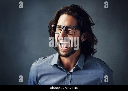Can you hear me now. Studio shot of a handsome young man shouting while posing against a grey background. Stock Photo