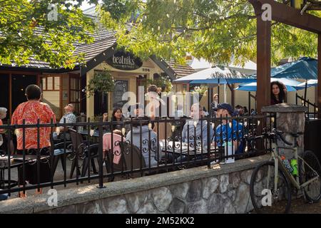 People sitting on crowded street at bar or restaurant outdoors in a city. People is having lunch in a terrace restaurant, relaxing and friendly moment Stock Photo