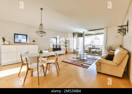 a living room with wood flooring and white furniture, including a dining table and two chairs in front of the window Stock Photo