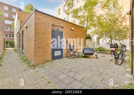 a bike parked in front of a brick building with a bicycle leaning against the wall on the side of the building Stock Photo