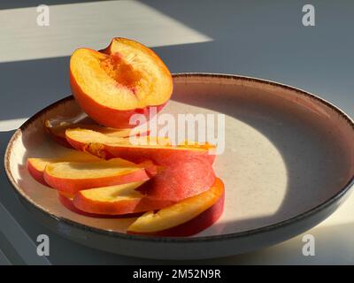 Sliced peaches and nectarines on a biege plate Stock Photo