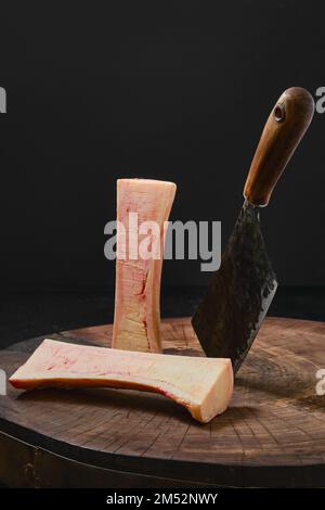 Large beef bone marrow chopped with cleaver on half on wooden stump Stock Photo