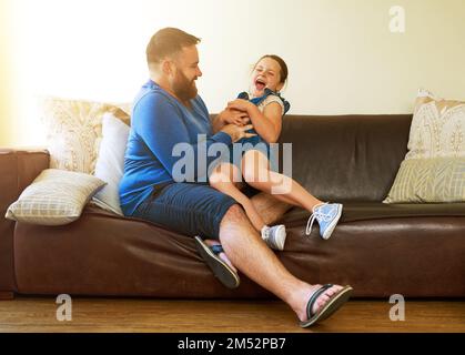 Lots of tickles and a whole lotta giggles. an adorable little girl getting tickled by her father at home. Stock Photo