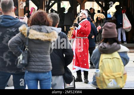 Munich, Deutschland. 24th Dec, 2022. Street musician disguised as a Weihaftertsmann plays the saxophone. Musician, street musician. Passers-by, people in the busy, crowded pedestrian zones in Munich on December 24th, 2022. Customers, people, Kaufinger Strasse, Neuhauser Strasse, Christmas time, Christmas Eve. ? Credit: dpa/Alamy Live News Stock Photo