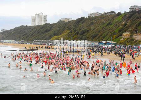 Boscombe, Dorset, UK.  25th December 2022.  UK Weather. Hundreds of Christmas Day revellers wearing festive fancy dress take the plunge in to the cold sea at Boscombe at Bournemouth in Dorset for the Macmillan White Christmas Dip charity swim on a cold overcast morning.  Picture Credit: Graham Hunt/Alamy Live News Stock Photo