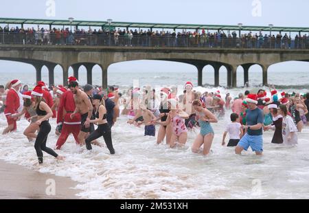 Swimmers take part in the Macmillan Boscombe White Christmas Dip, in aid of Macmillan Caring Locally, at Boscombe Pier, Bournemouth, Dorset. Picture date: Sunday December 25, 2022. Stock Photo